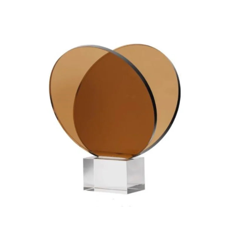 رف كتب ومجلات من ديكوربايتس™ مصنوع من الأكريليك والكريستال، مزين بزخارف هندسية دائرية، وتماثيل صغيرة من العنبر