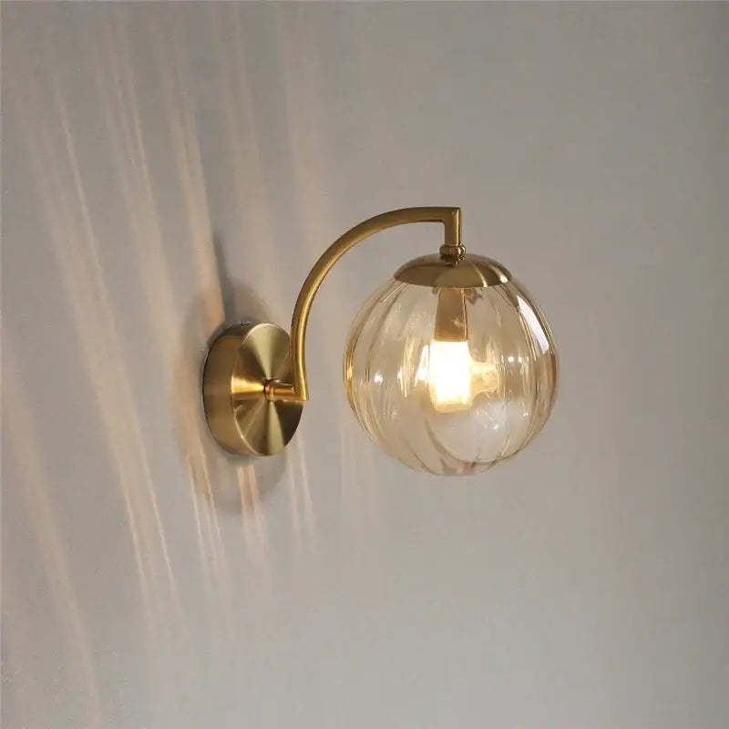 Brass-finished wall lamp with a textured amber-tinted glass globe for bedroom decorbites colored glass ball lighting