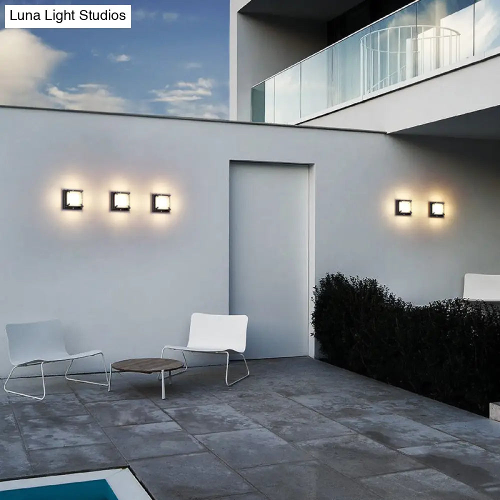 Aplique de pared cuadrado contemporáneo para patio DecorBites™ con luz LED, en color negro con cristal esmerilado.