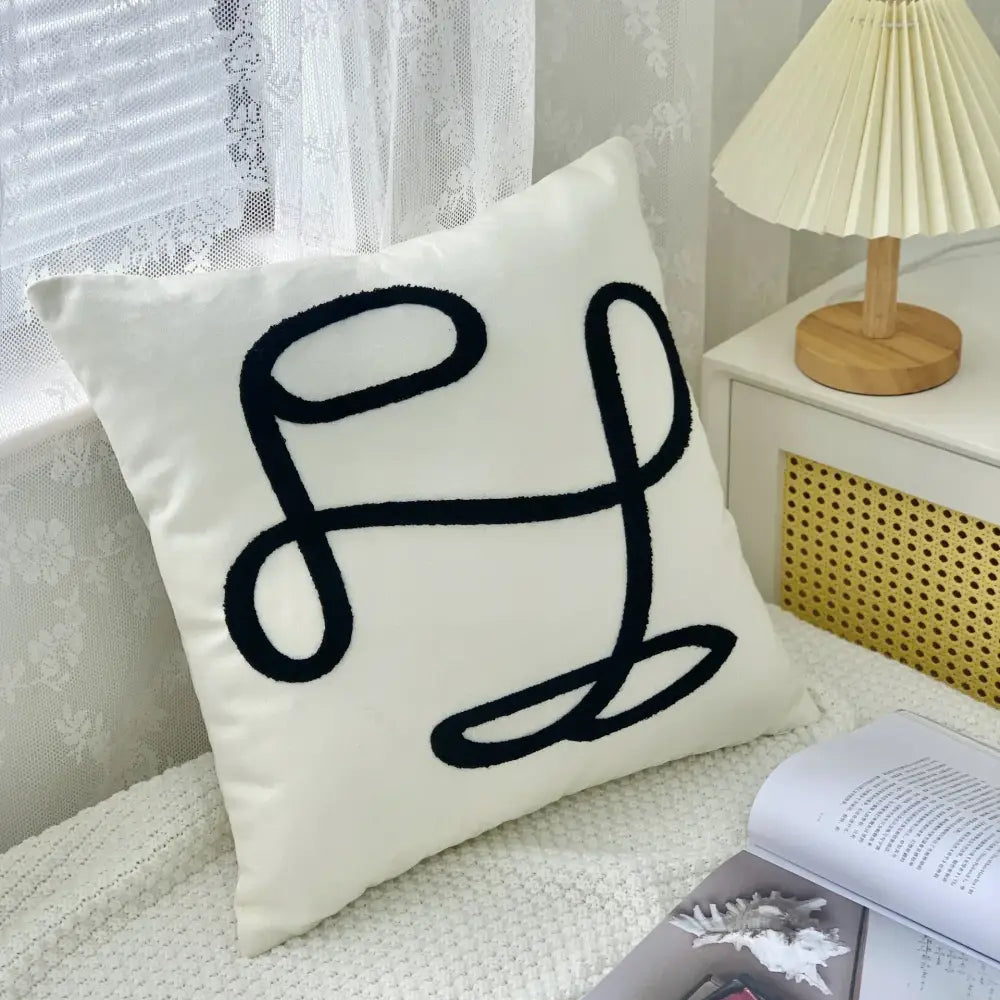 Cream-colored cushion cover with bold black embroidered abstract art line monogram by DecorBites abstract art