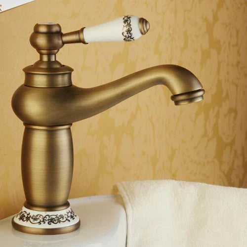 Antique bronze DecorBites™ single handle bathroom faucet with brass finish and white ceramic base with black floral patterns real shot details