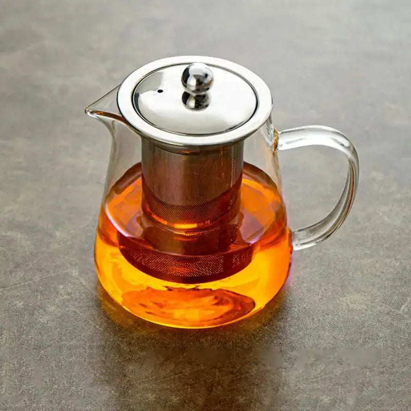 Clear glass tea jug set with stainless steel lid and built-in filter holding orange tea from decorbites