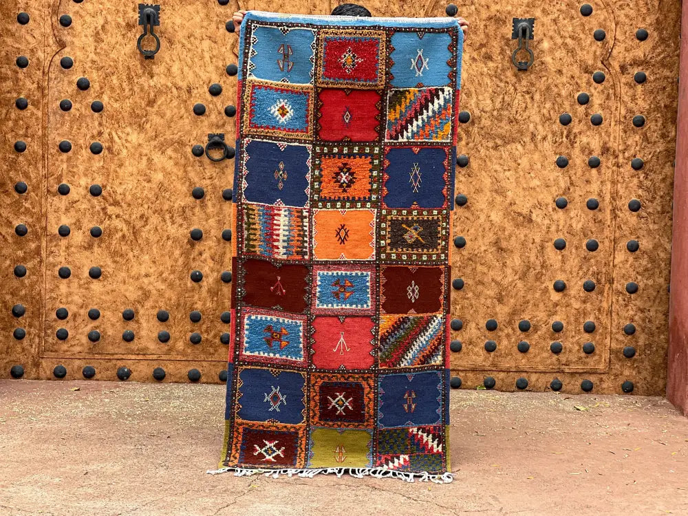Vibrant moroccan handmade taznakht rug with intricate geometric patterns in bold red blue orange and green tones 200cm x 70cm