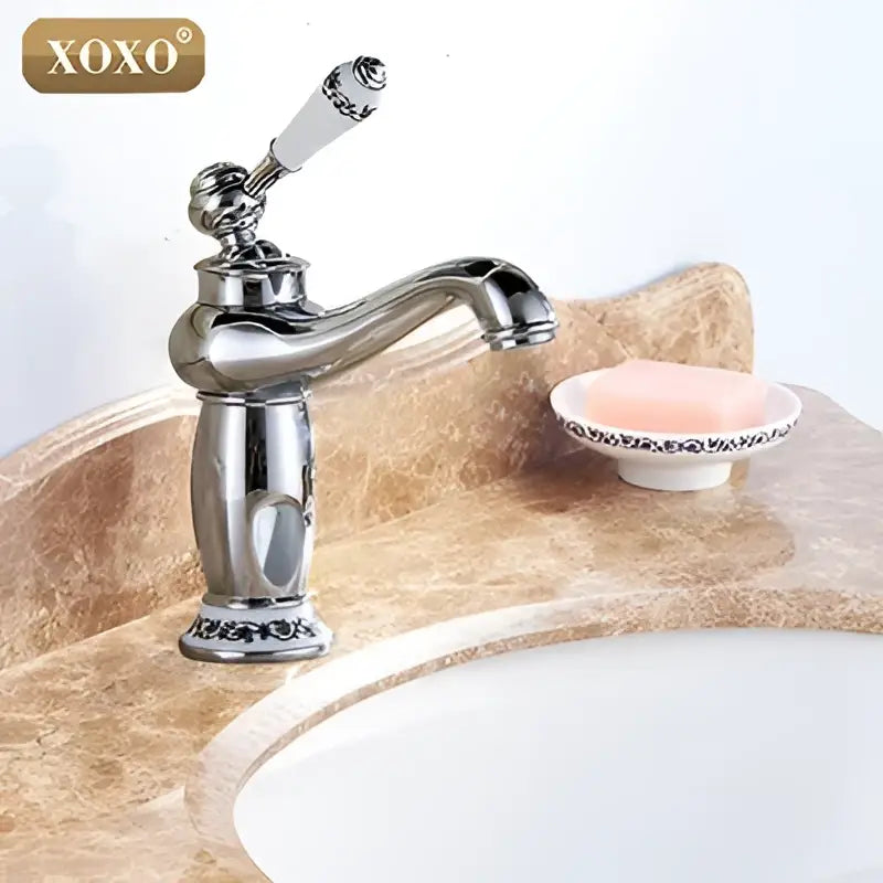 Chrome finished deck mounted decorbites bathroom basin faucet with white ceramic handle and ornate detailing