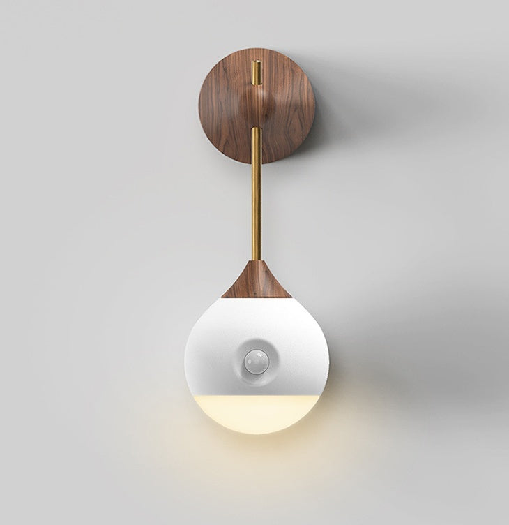 Modern wooden and brass wall sconce with a white globe shade.