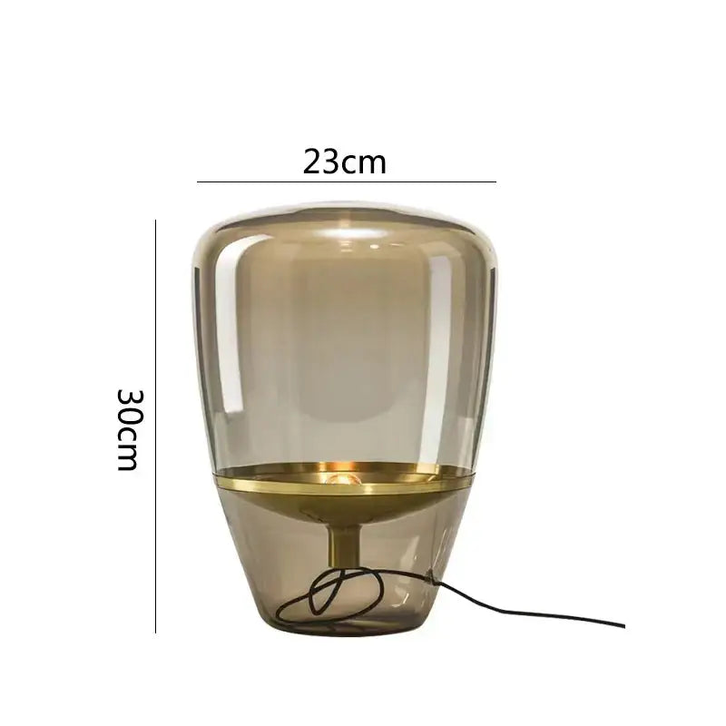 A sleek amber-tinted decorbites glass table lamp with brass accent and minimalist design for bedroom led lighting
