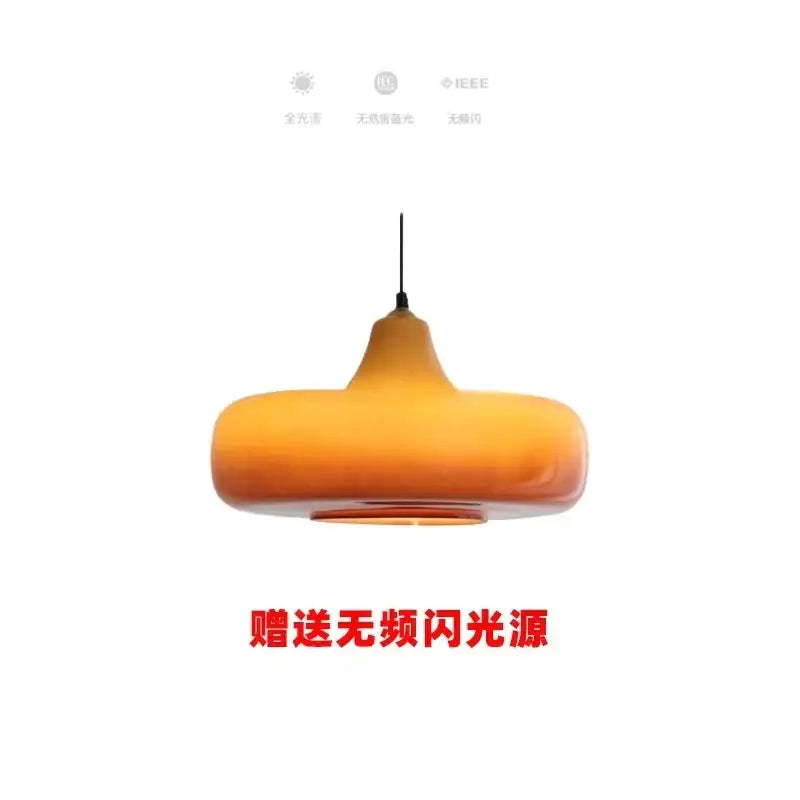 A warm amber-colored glass pendant light with a smooth teardrop shape for modern dining room lighting
