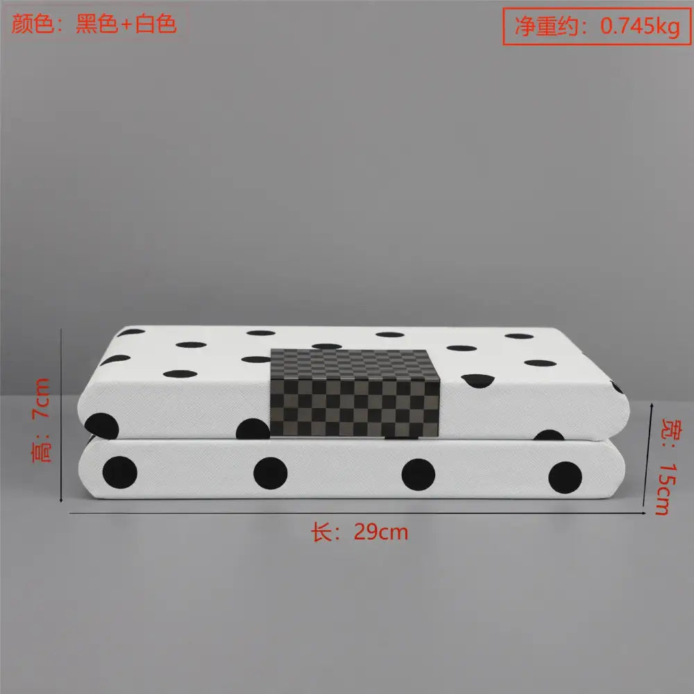 Modern white and black polka dot leather storage box with a white rectangular cushion featuring black polka dots and a checkered panel
