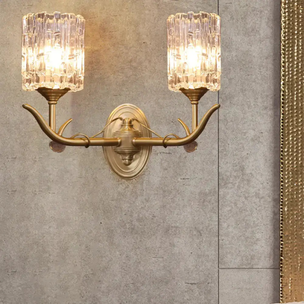 Antique brass two-light wall sconce with clear glass faceted shades and gold finish suitable for 220v-240v corridors