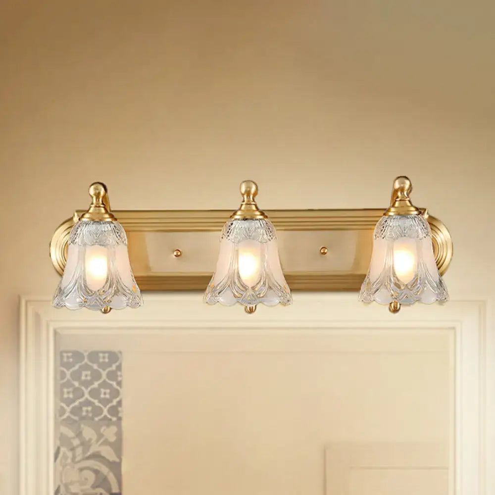 Vintage gold wall light with three clear glass shade bell-shaped lights featuring intricate cut patterns for bathroom vanity lighting