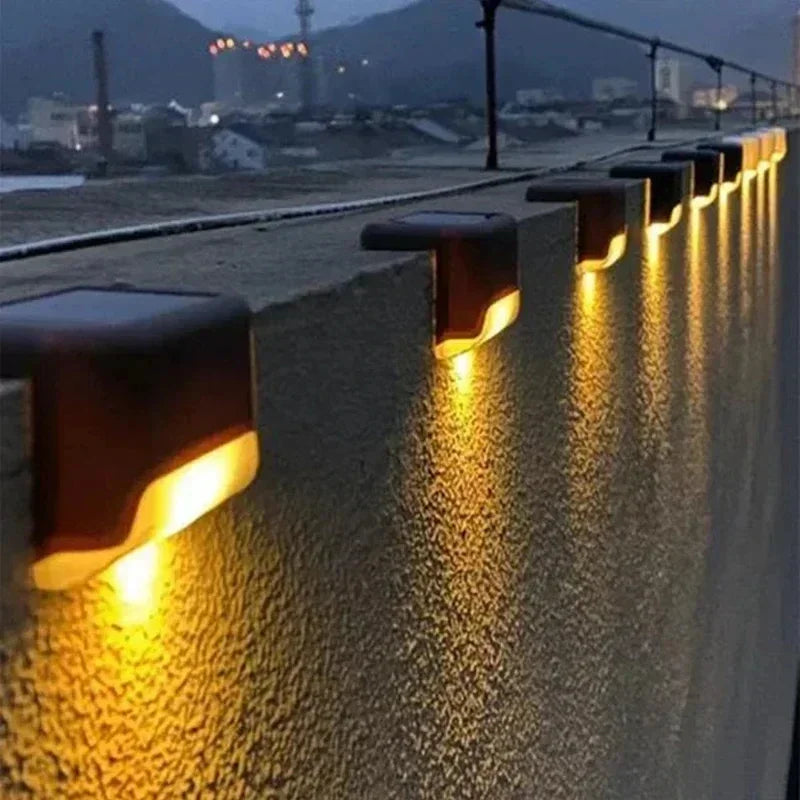 Warm yellow led solar pathway lights with dark brown plastic housing mounted on textured concrete wall for outdoor use