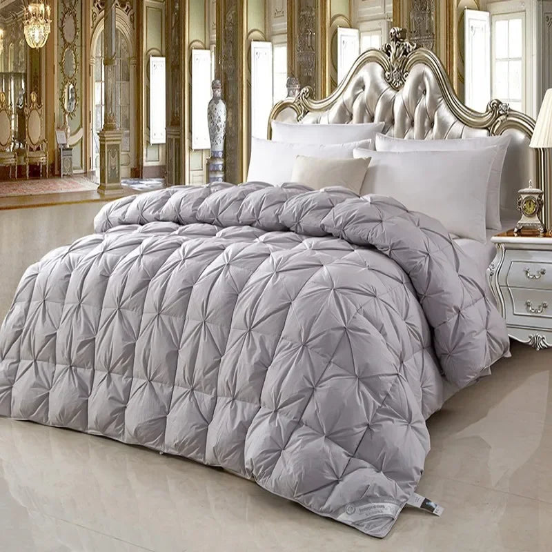 A plush light gray quilted 100% white goose down comforter with diamond stitching on an ornate bed for winter use