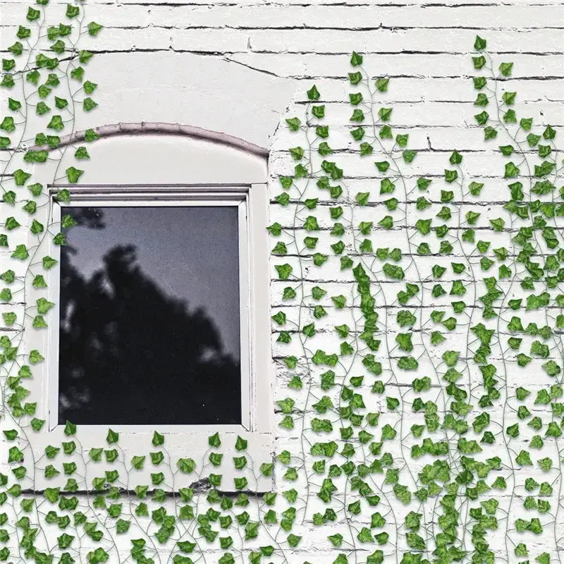 Green ivy garland string with detailed leaves and thin stems covers a white brick wall around an arched window decorbites 12pcs