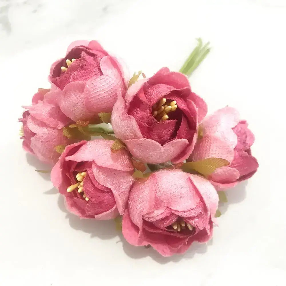 A cluster of five pink fabric flowers with textured petals and yellow centers from 200pcs mixed rose red stamen bundle