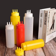 Set of colorful plastic squeeze bottle condiment dispensers with multi-spout caps in yellow red and clear varieties