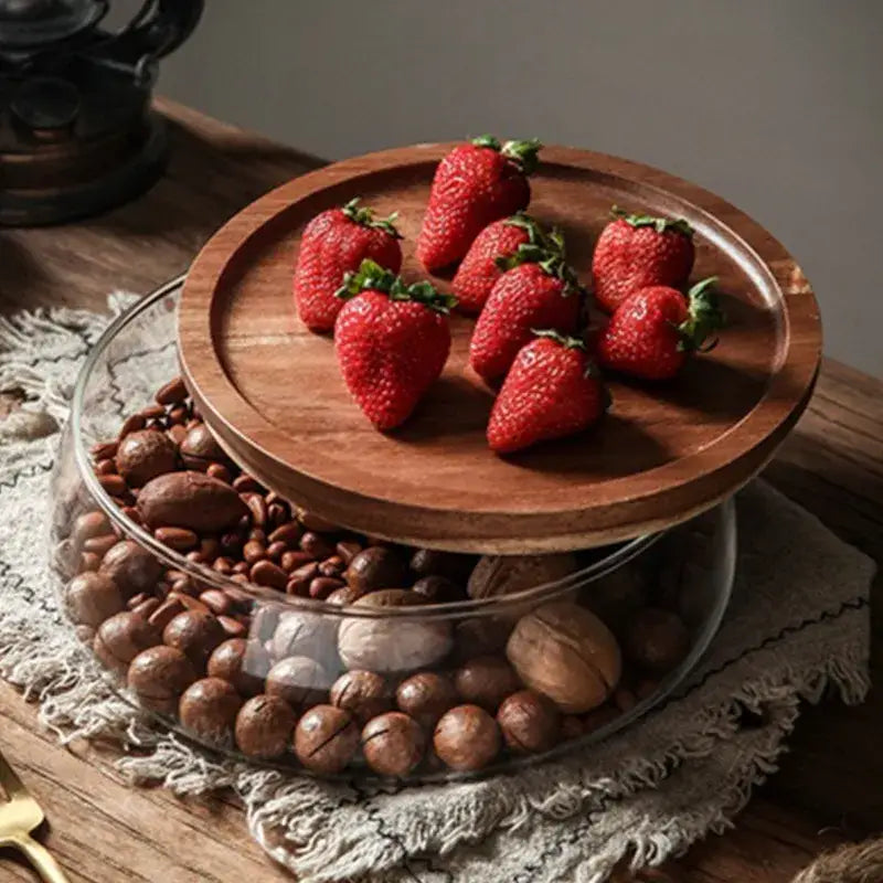A rustic wooden tray with red strawberries displayed alongside 3 tier glass food storage containers with wood stand
