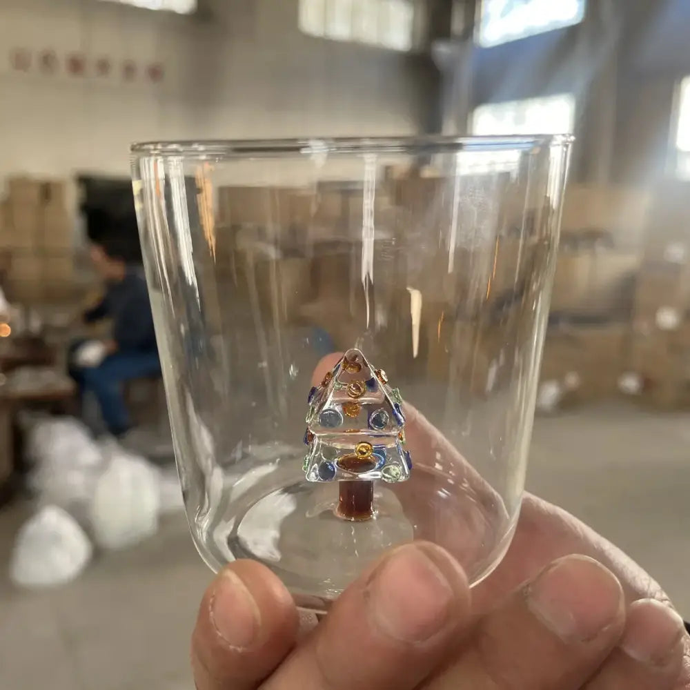 A clear glass 300ml 3d christmas tree wine glass featuring a detailed blue and gold christmas tree ornament inside