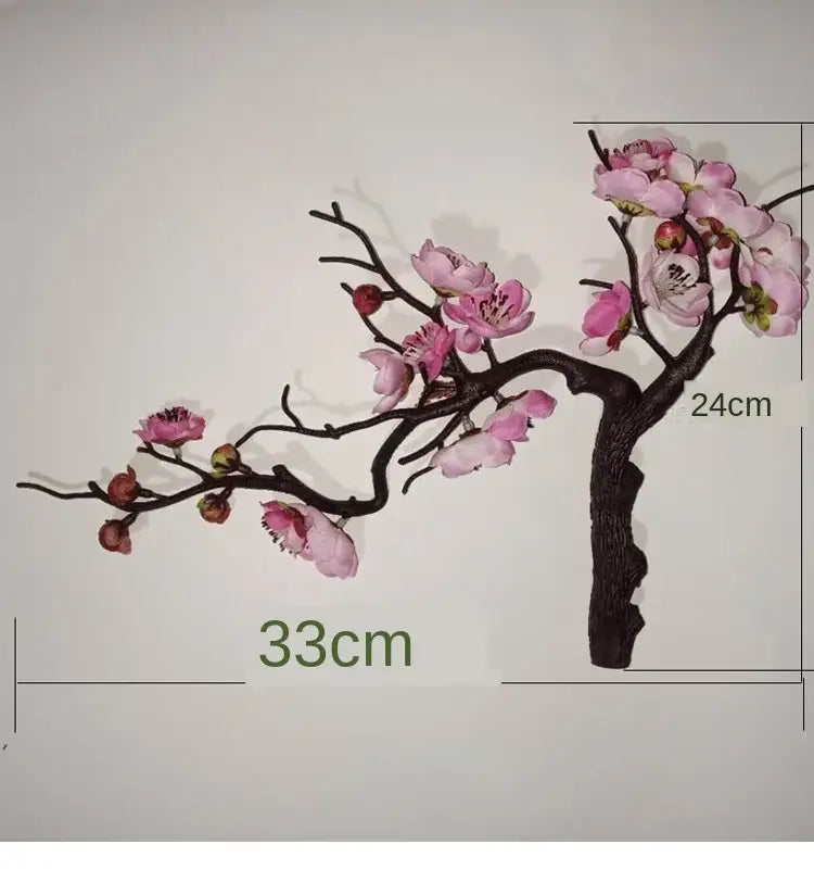 Decorative artificial cherry blossom branch with pink flowers and dark brown textured branches in ceramic vase for dried flowers