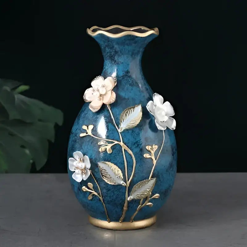 Deep blue ceramic vase with gold-trimmed rim and base, white floral appliqués, ideal for dried flowers display
