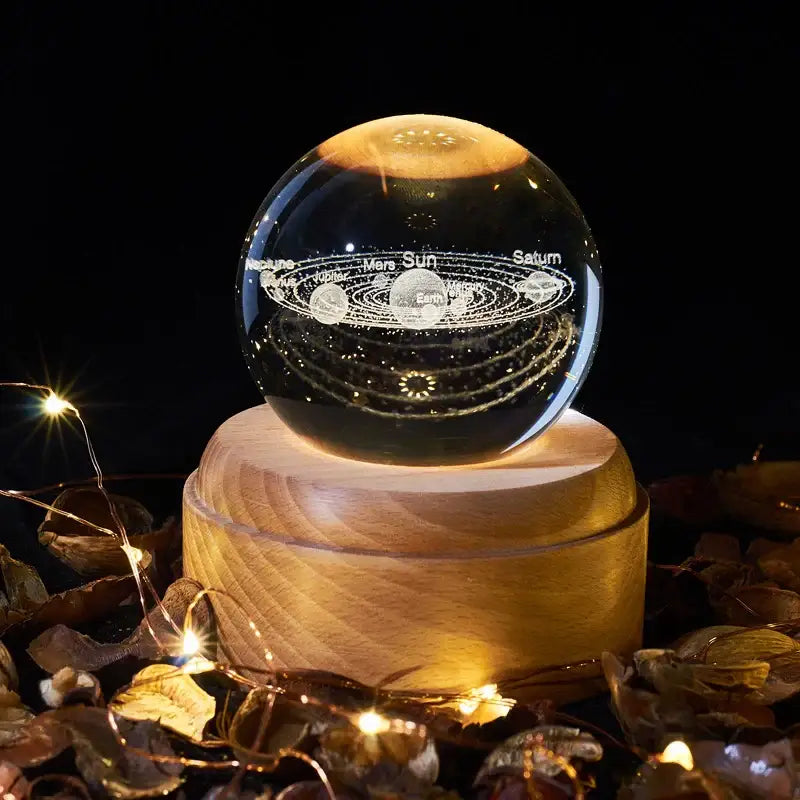 A clear crystal ball night light with an engraved solar system on a wooden base from decorbites crystal ball