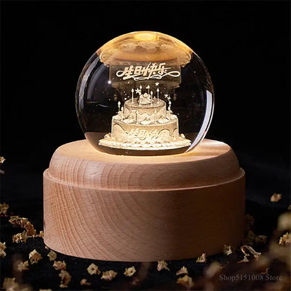 A golden birthday cake decorbites crystal ball night light inside a glass sphere on a wooden music box base