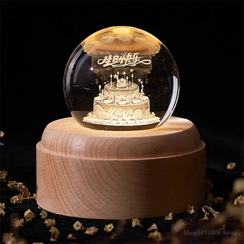 A golden birthday cake decorbites crystal ball night light inside a glass sphere on a wooden music box base
