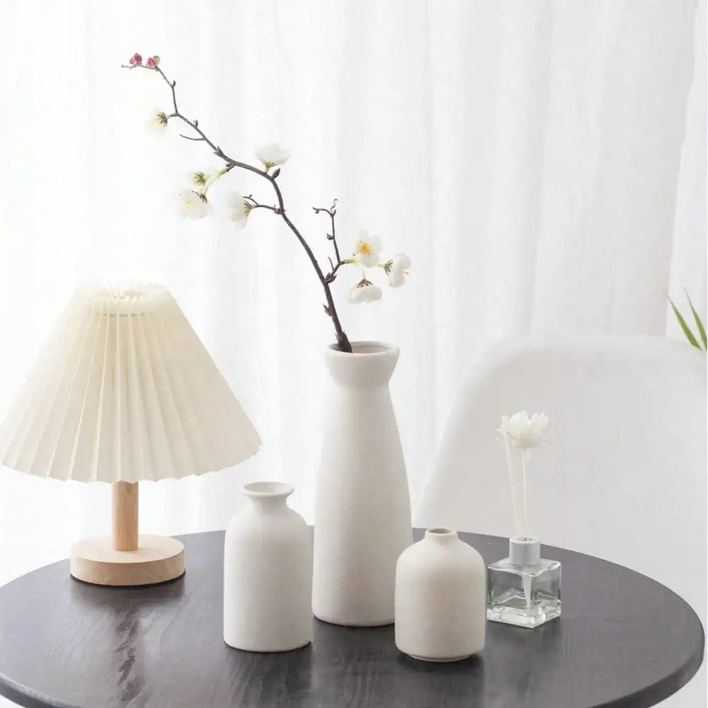 A tall slender white ceramic vase with a smooth matte finish and flared neck from a 3pcs bohemian vase set for home decor