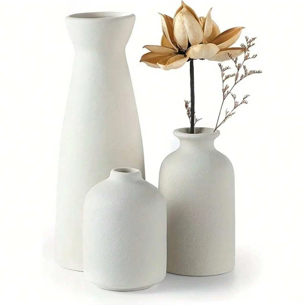 Set of three minimalist white ceramic vases with textured surfaces and dried golden lotus flower for home decor