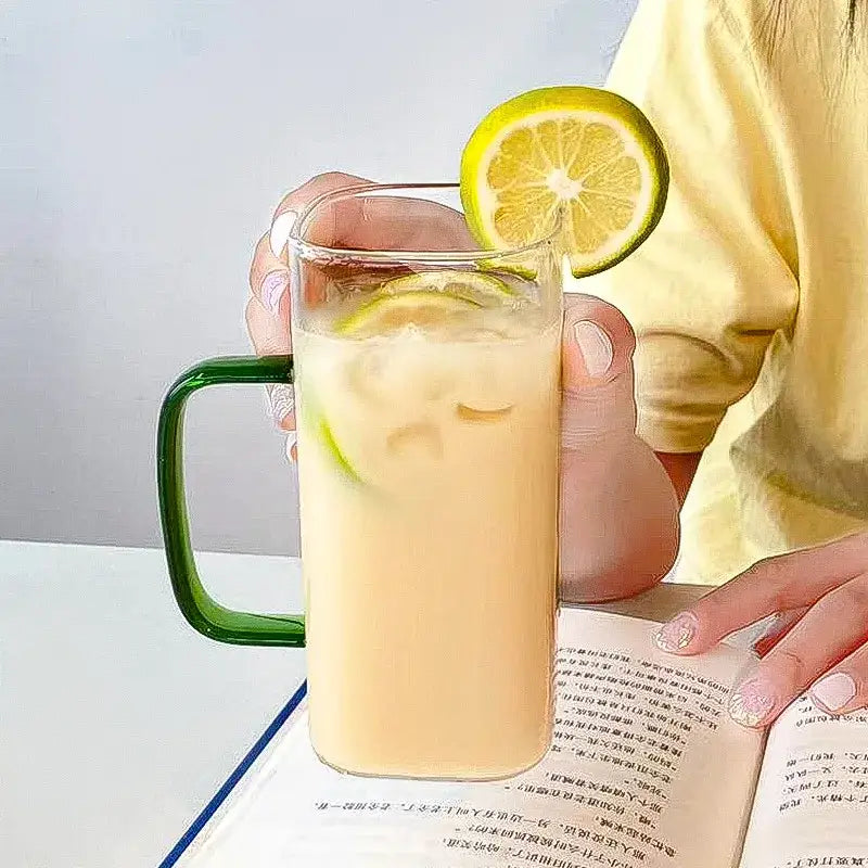 A 400ml square glass mug with vibrant green handle holds iced beverage with lemon slices and bamboo lid and straw
