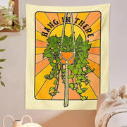 Beige 70s retro decorbites botanical tapestry wall hanging with green leafy plant in macrame hanger and sunburst background