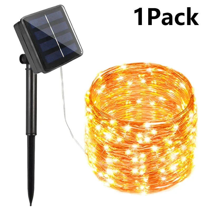 Golden copper-colored solar-powered string fairy lights with warm white led bulbs connected to black solar panel stake