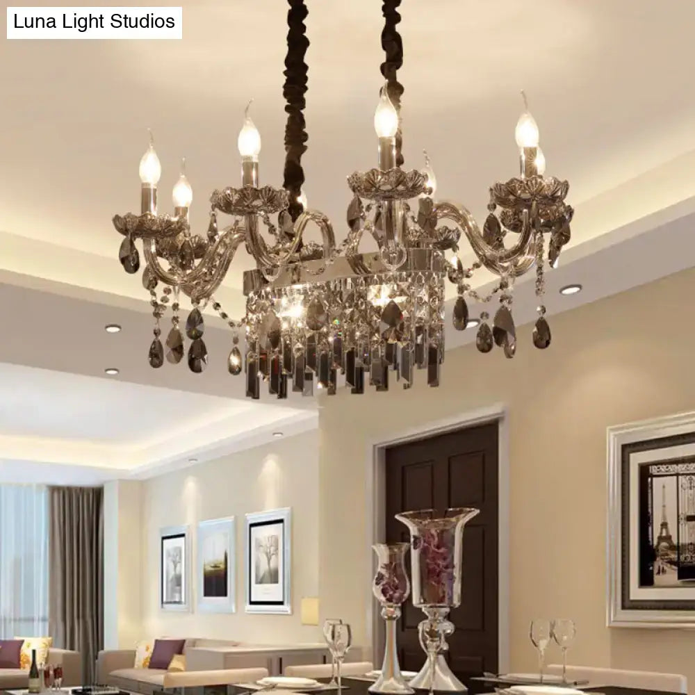 An ornate decorbites smoke gray crystal 8-light island pendant with candle-style bulbs and glass lamp saucer