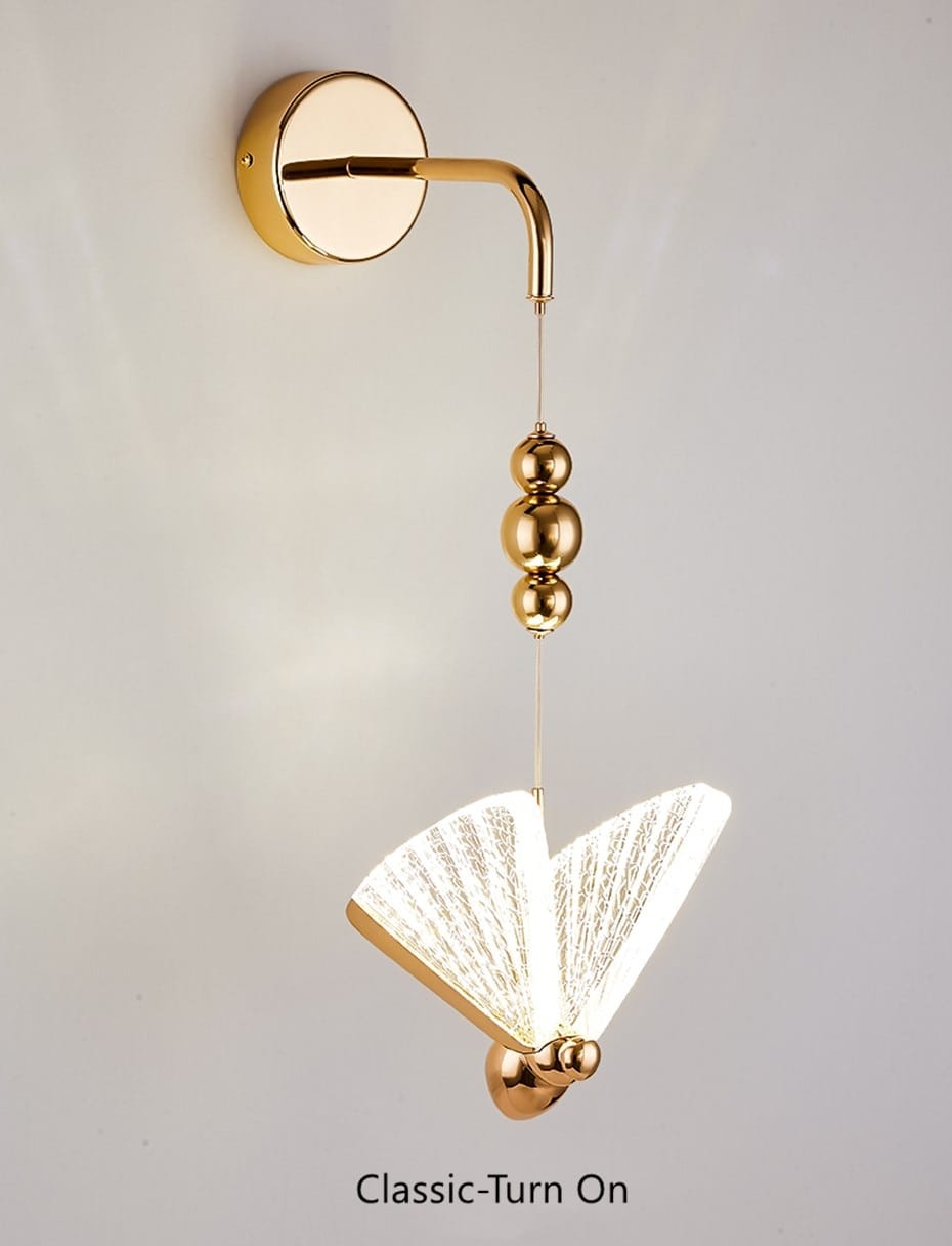 Gold-finished butterfly led wall light for bedroom featuring a fan-shaped translucent diffuser and three spherical beads along the hanging chain, designed as a nordic butterfly led wall light.
