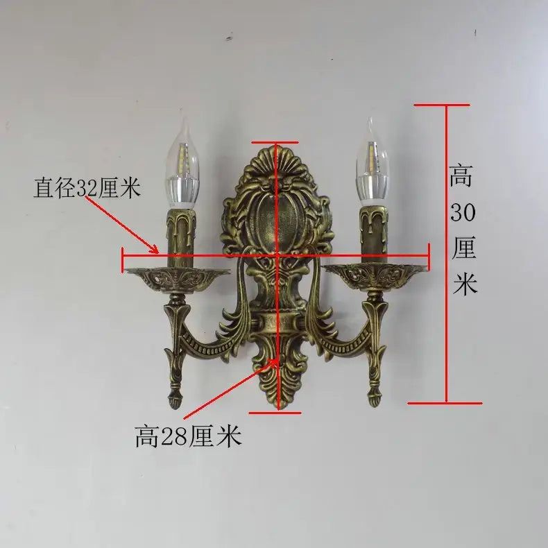Antique brass two-light wall sconce with ornate scrollwork and candle-style arms designed for creative retro european bedroom use as a retro european wall light.