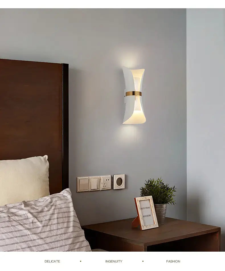 Modern white wall lamp with a gold accent band and curved design for bedroom lighting.