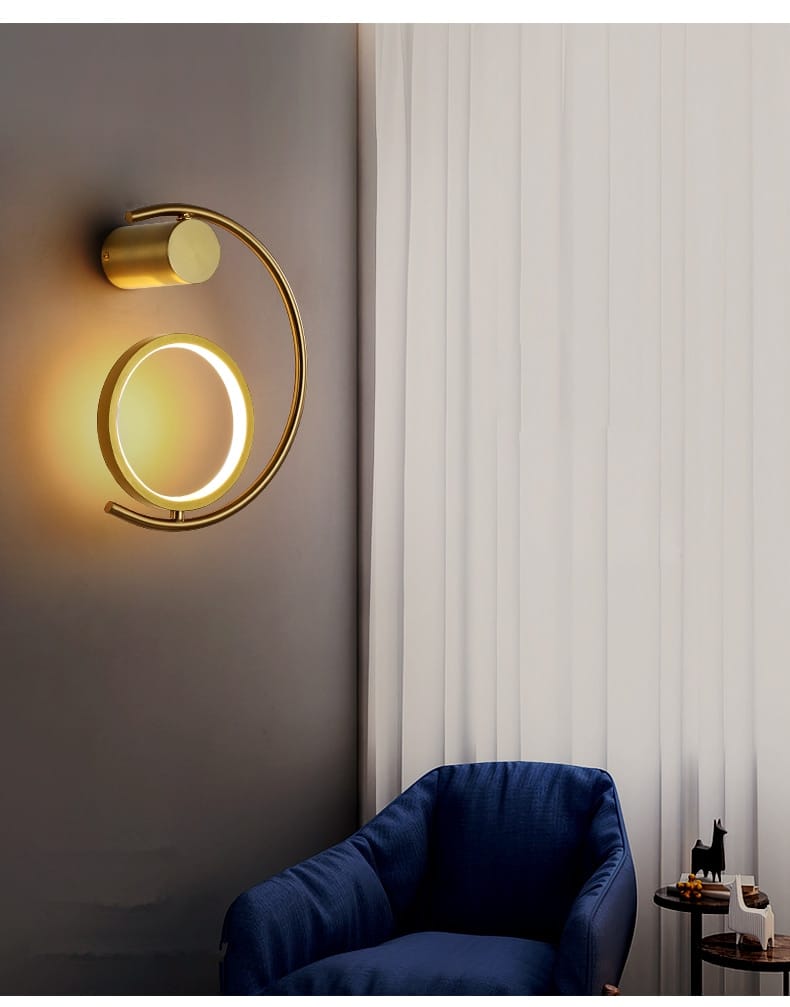modern gold luxury creative led bedside wall sconce featuring a gold-toned circular ring and cylindrical fixture emitting warm ambient light for bedroom use.