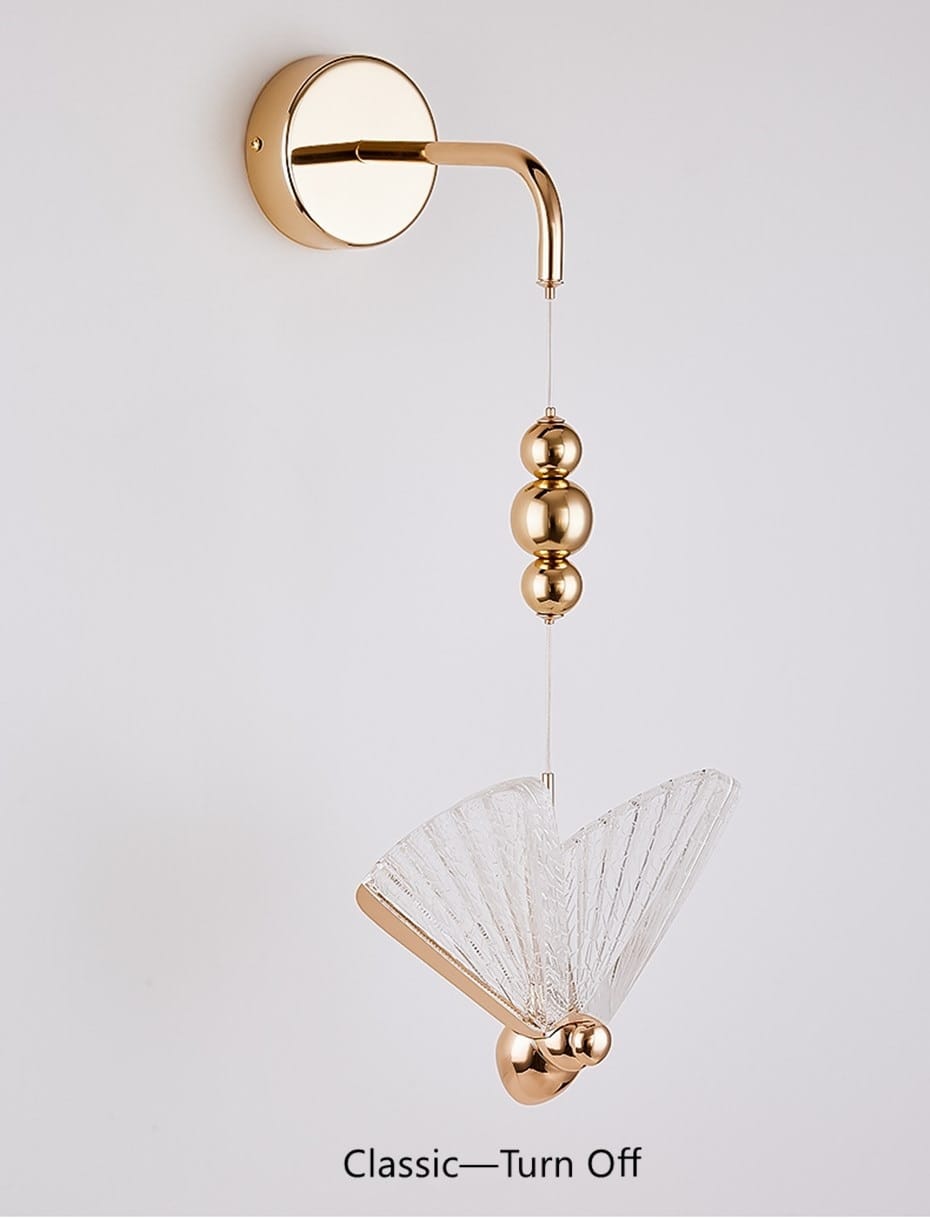 gold and patterned butterfly led wall light featuring a gold-finished wall sconce with a clear fan-shaped glass shade and three spherical brass beads hanging from the curved arm, designed as a nordic butterfly led wall light for bedroom use.