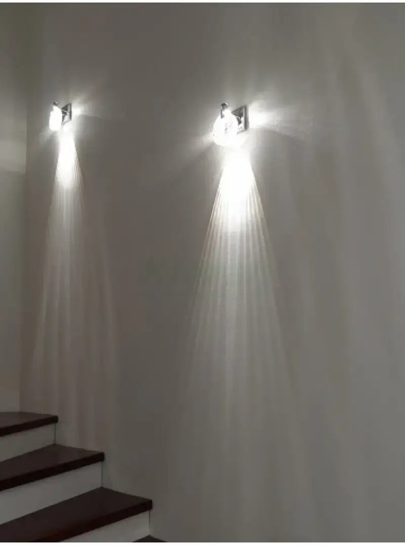 Two sleek modern gold crystal led wall lamps with metallic finish and three globe light design cast bright beams down the staircase as a simple crystal led lighting solution.