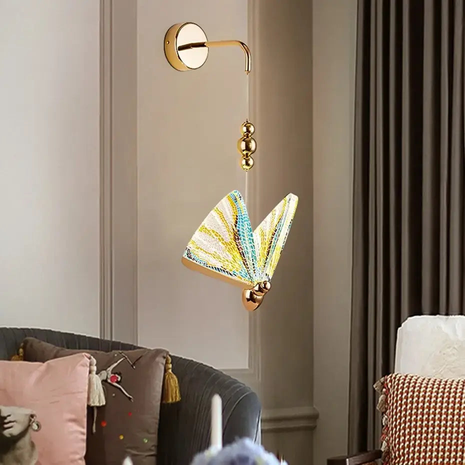Gold-toned butterfly led wall sconce with iridescent yellow teal and white patterned wings designed as a nordic butterfly led wall light for bedroom use.