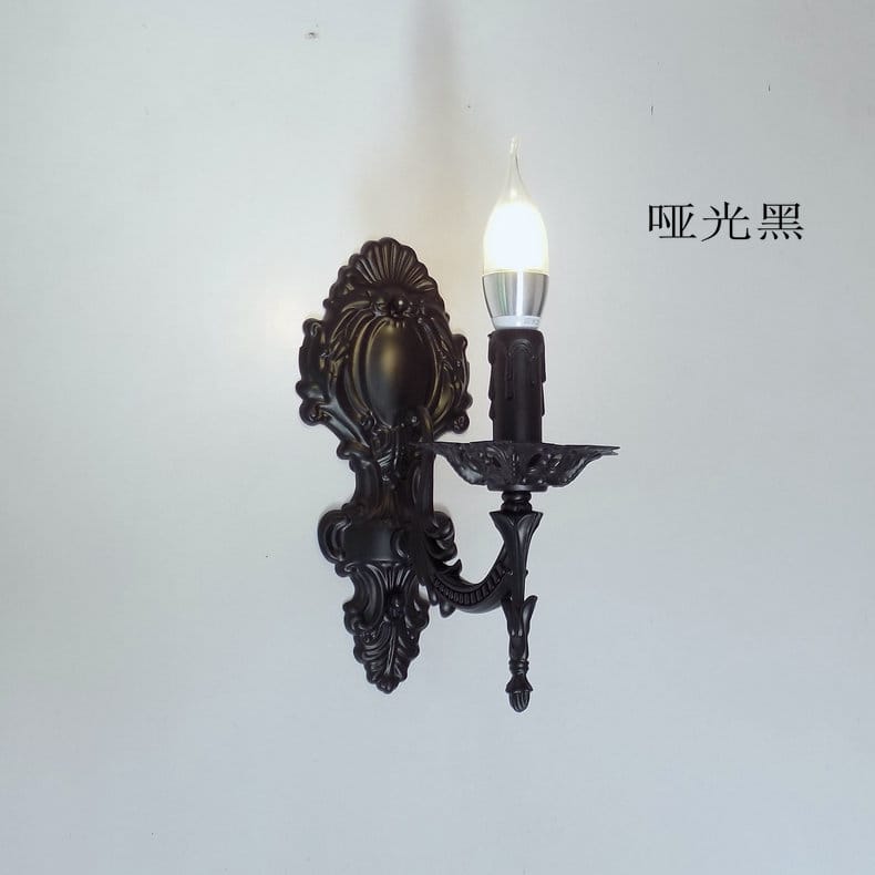 Matte black ornate wall sconce with intricate scrollwork and a candle-style bulb designed as a creative retro european wall light for bedrooms.