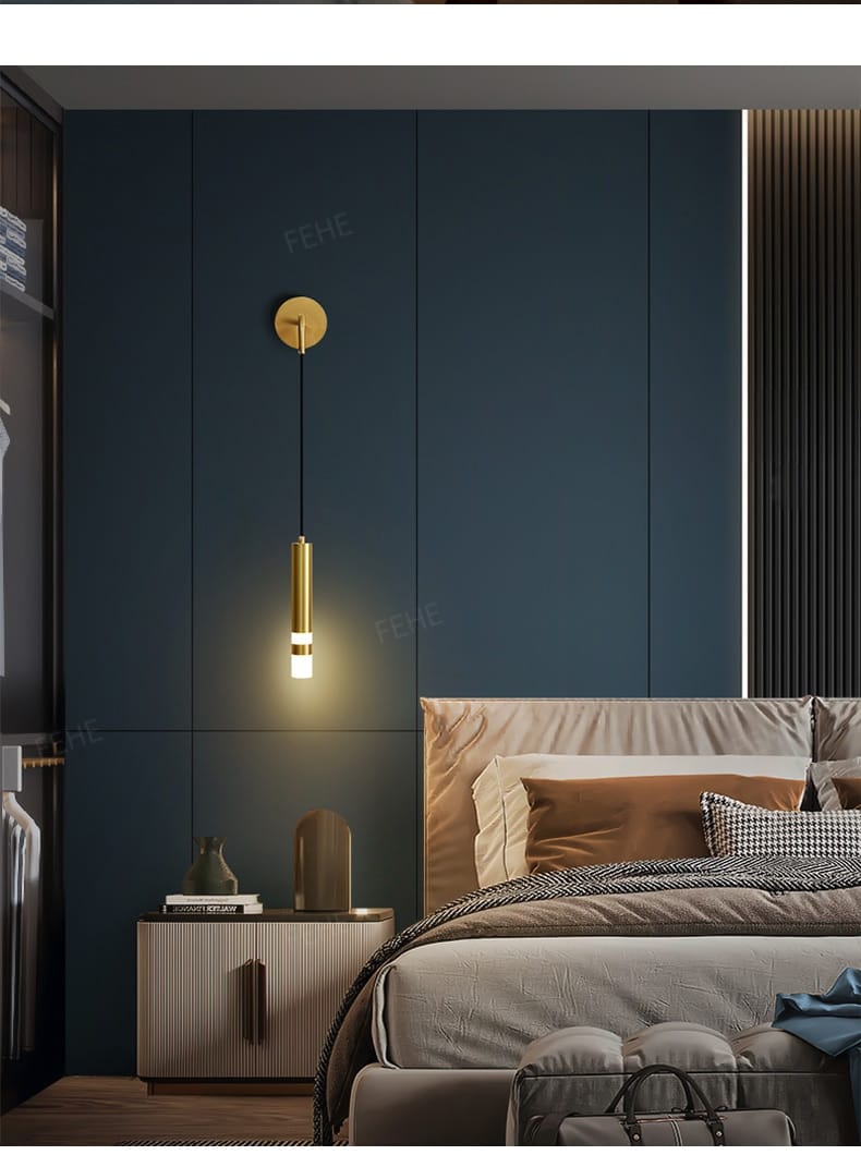 Gold-toned cylindrical pendant light with a sleek modern design hanging from a circular wall mount for a minimalist creative luxury bedroom bedside wall lamp.