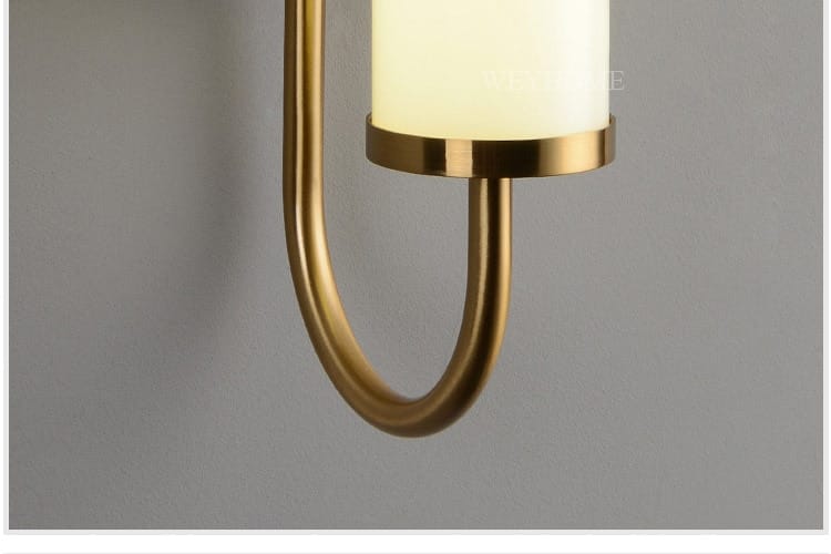 Modern minimalist gold led wall lamp featuring a gold-toned curved metal arm and an off-white cylindrical glass shade for bedroom lighting.