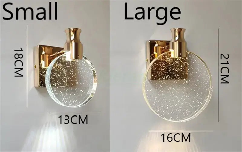 Modern gold crystal led wall lamp featuring a gold-toned wall sconce with a circular clear glass shade embedded with glittery specks designed as a simple crystal led for bathroom use.