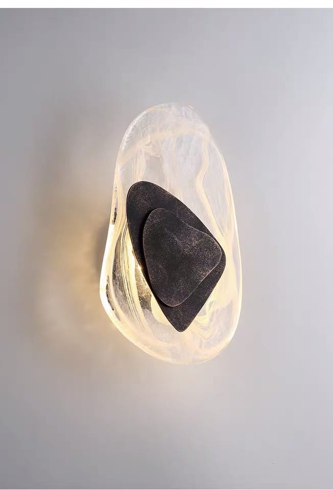 a modern creative minimalist glass wall lamp featuring a translucent organic-shaped sconce with a warm glow and two nested dark gray stone-like accents, ideal for bedroom bedside lighting
