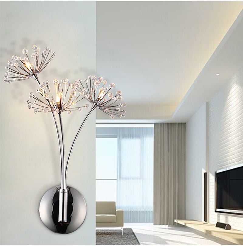Modern chrome-finished nordic creative crystal wall lamp featuring three dandelion-like arms with sparkling crystal flower accents for bedroom use.