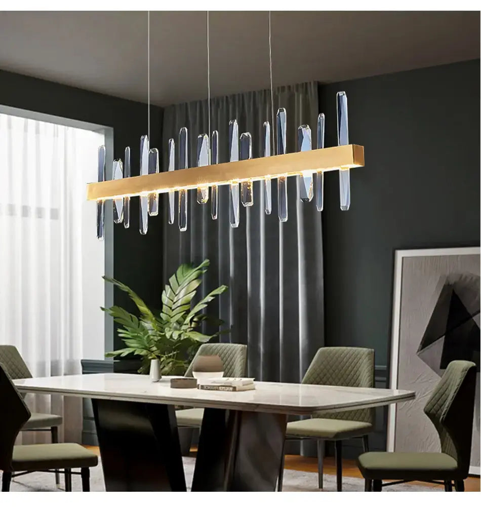 Modern rectangle gold crystal chandelier featuring a gold-toned rectangular pendant with clear crystal-like vertical rods hanging for dining room lighting.