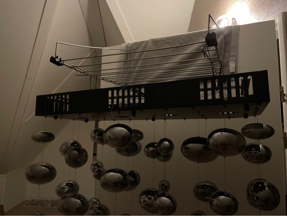 a modern oval bubble ball silver chandelier dining room light fixture with a black rectangular base, silver metal frame, and multiple spherical chrome balls suspended below
