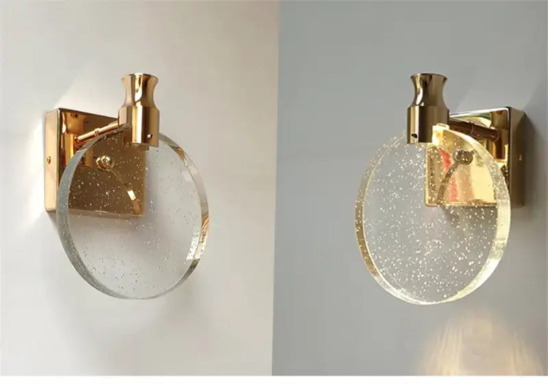 modern gold crystal led wall lamp featuring a gold-finished wall sconce with a circular clear glass shade with subtle internal speckles designed for bathroom use.