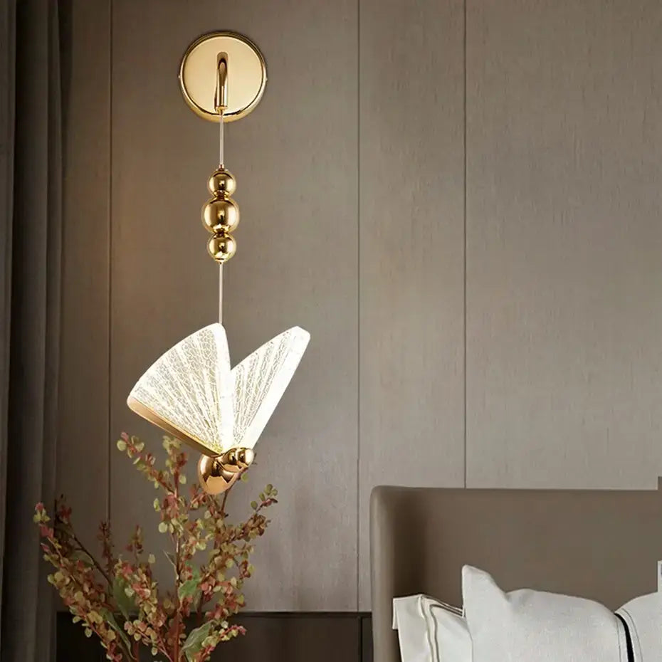 Gold-finished wall light with a fan-shaped translucent white glass shade and three spherical decorative beads on the hanging chain for bedroom butterfly led wall lighting.