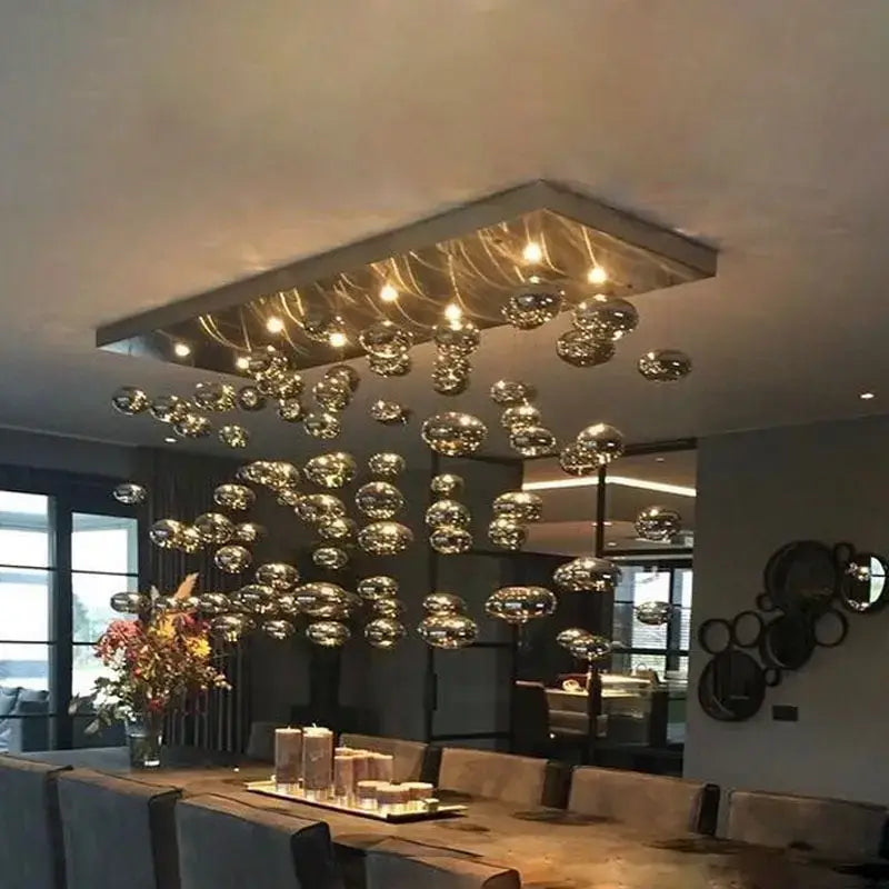 Modern oval bubble ball silver chandelier with hanging glass globe lights suspended from a metallic frame for dining room lighting.